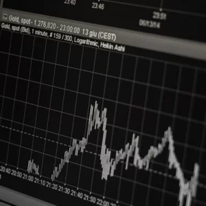 Close-up of financial market charts displayed on computer screens, showing fluctuating stock prices and economic data trends.